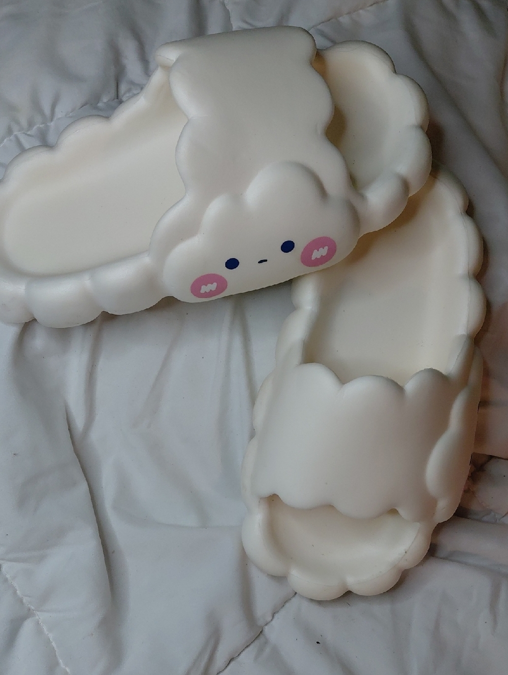 These are white Boogzel cloud foam street slippers featuring a cute face.
